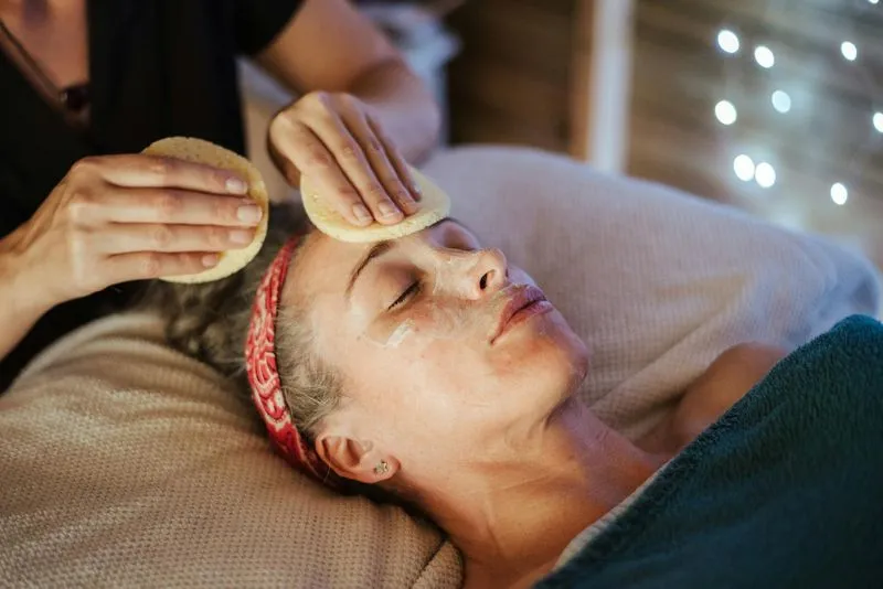 A woman laying on a bed with a hair dryer on her head.