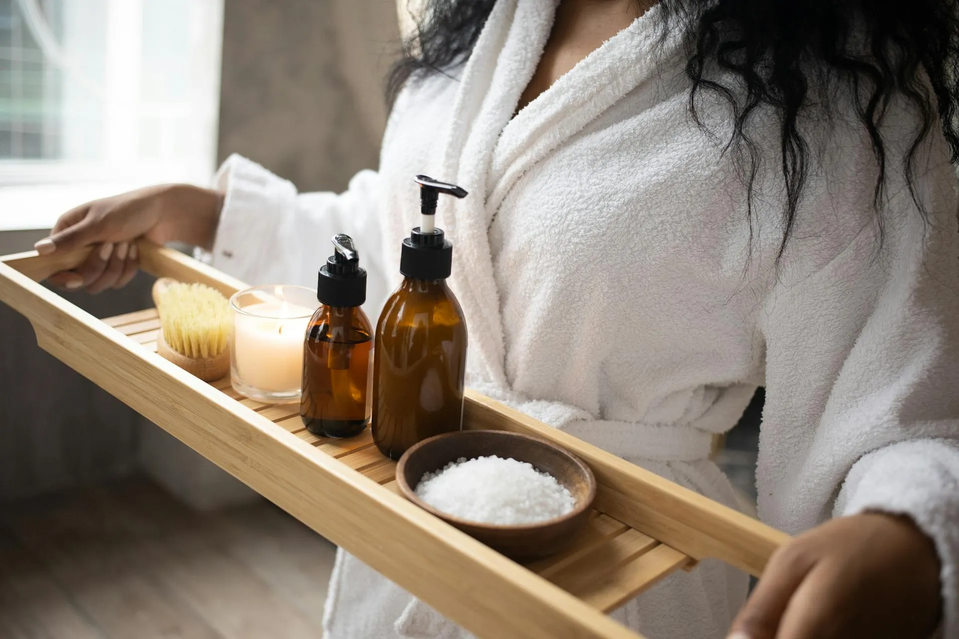 A woman in a bathrobe is holding a tray of soaps and a.