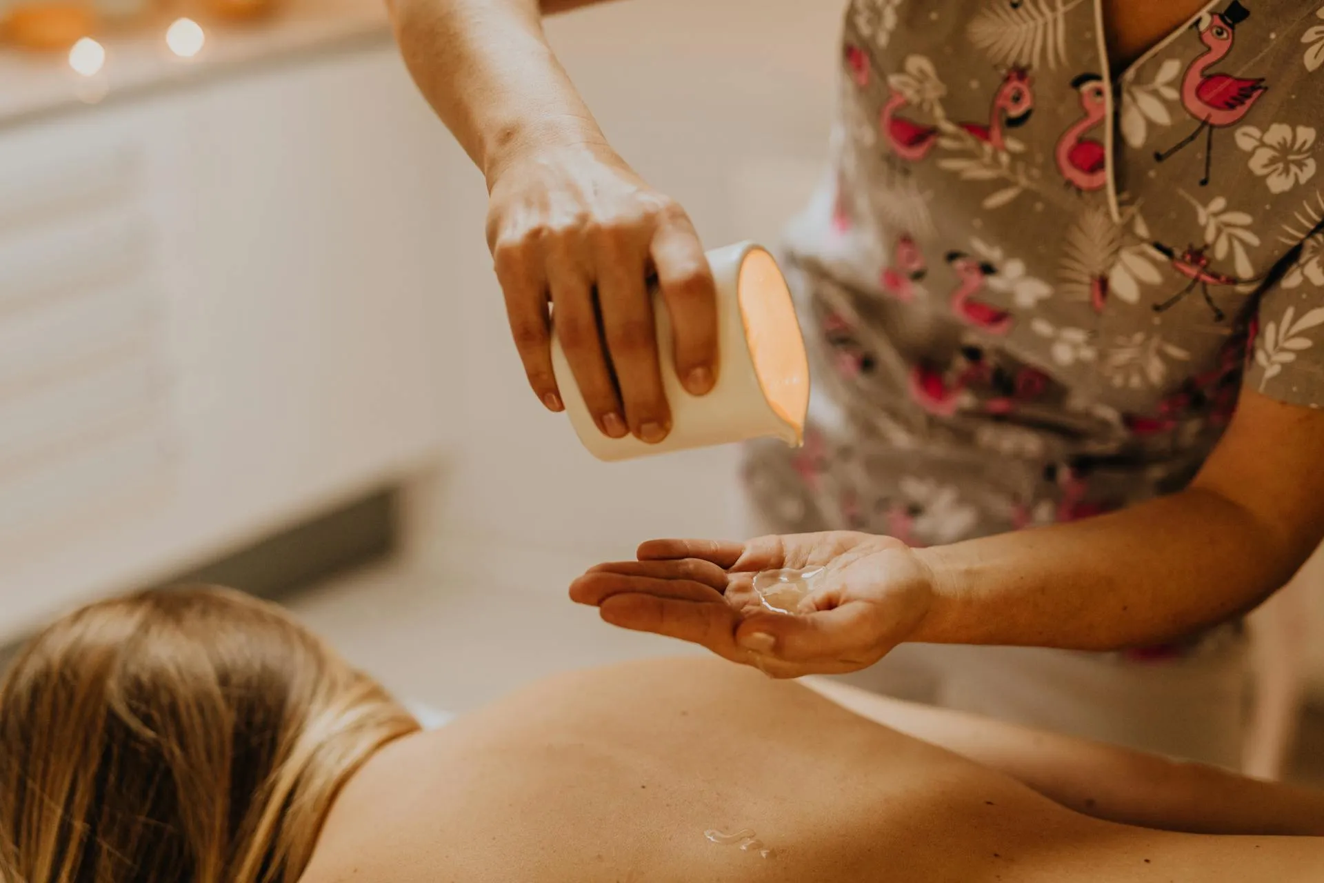 A woman getting a back massage with a bottle of lotion.