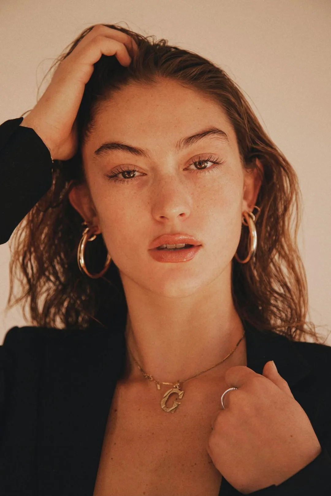 A woman wearing large hoop earrings and a black jacket.